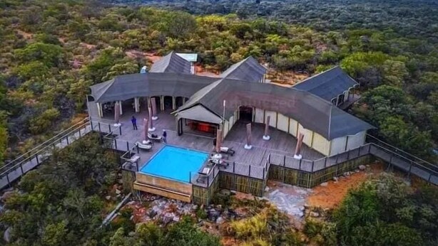 Une vaste villa moderne dotée d’une piscine, entourée d’une végétation luxuriante et offrant une vue dégagée sur le paysage.