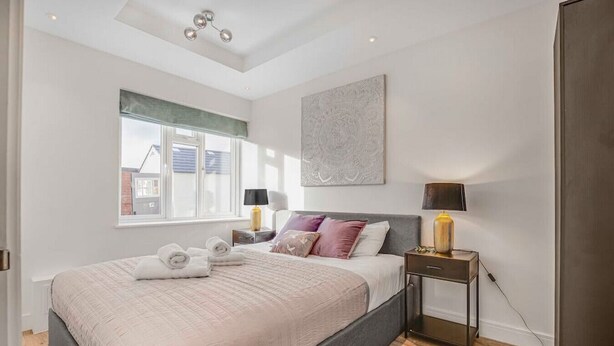 Une chambre moderne avec un grand lit, une table de chevet avec des lampes, une fenêtre donnant sur un beau paysage et un luminaire au plafond.