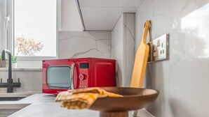 Une cuisine avec un micro-ondes rouge, un saladier en bois et une cuillère en bois posés sur le comptoir.