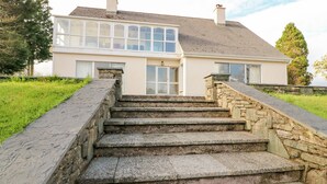 Una casa de dos pisos con una escalera de piedra que lleva a la puerta principal.