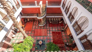 A courtyard with a spiral staircase, patterned rugs, and traditional architecture. - Riad Dar Nejma & Spa (Marrakech)