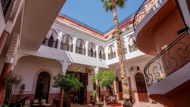 A courtyard with a palm tree, a fountain, and a dining area. - Riad Dar Nejma & Spa (Marrakech)
