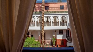 A view of a building with a balcony, a palm tree, and a small garden area. - Riad Dar Nejma & Spa (Marrakech)