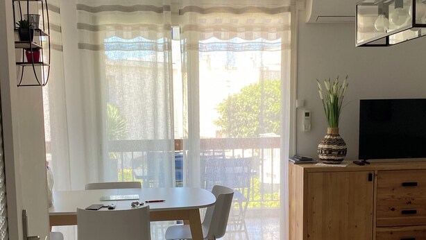 Un soggiorno moderno con zona pranzo, un mobiletto in legno e una TV.