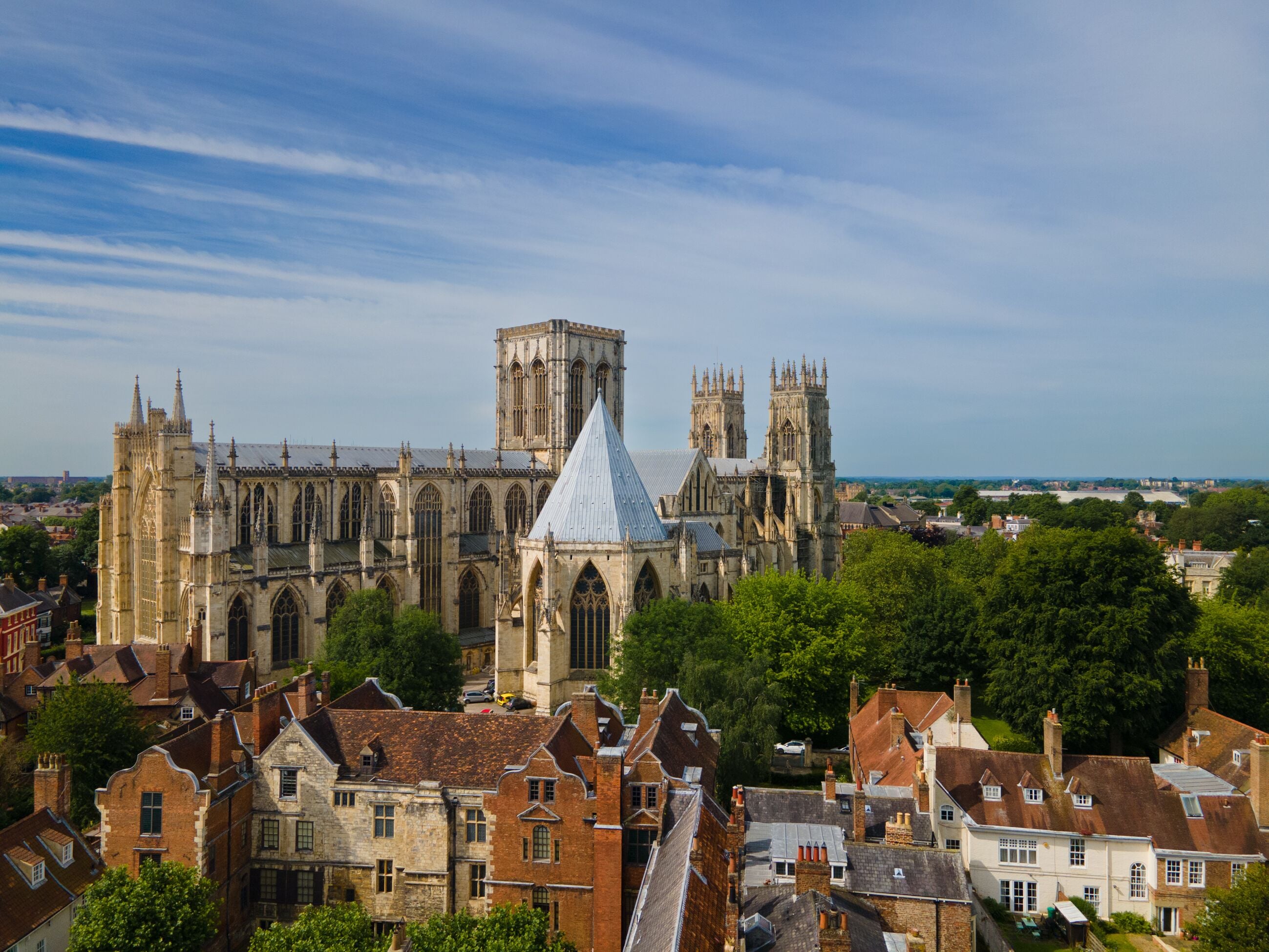 A historic cathedral with Gothic architecture, surrounded by traditional buildings and greenery.