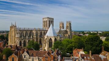 A historic cathedral with Gothic architecture, surrounded by traditional buildings and greenery.