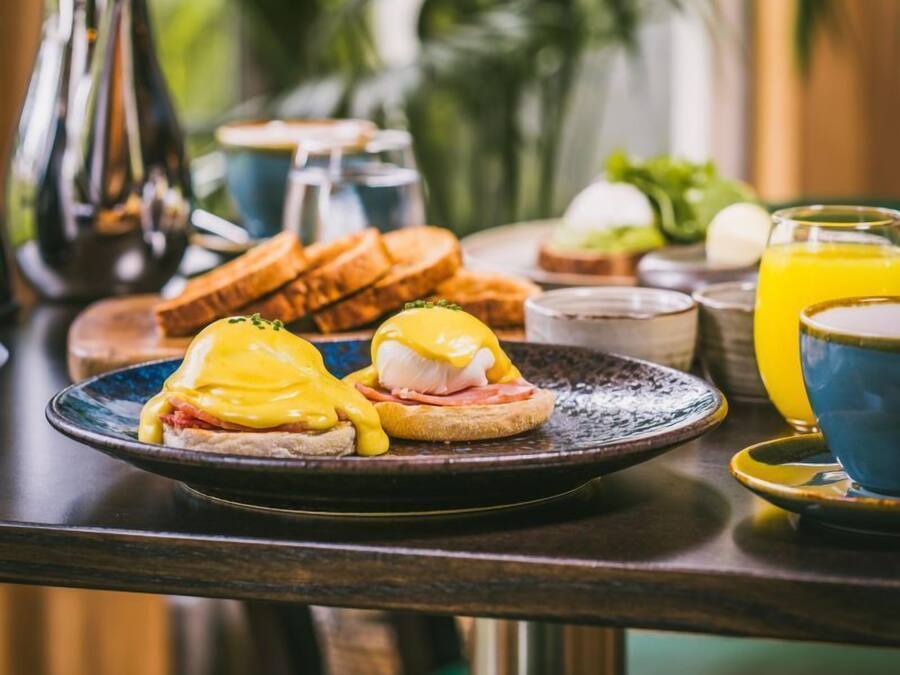 A breakfast table with eggs benedict, toast, and a glass of orange juice.