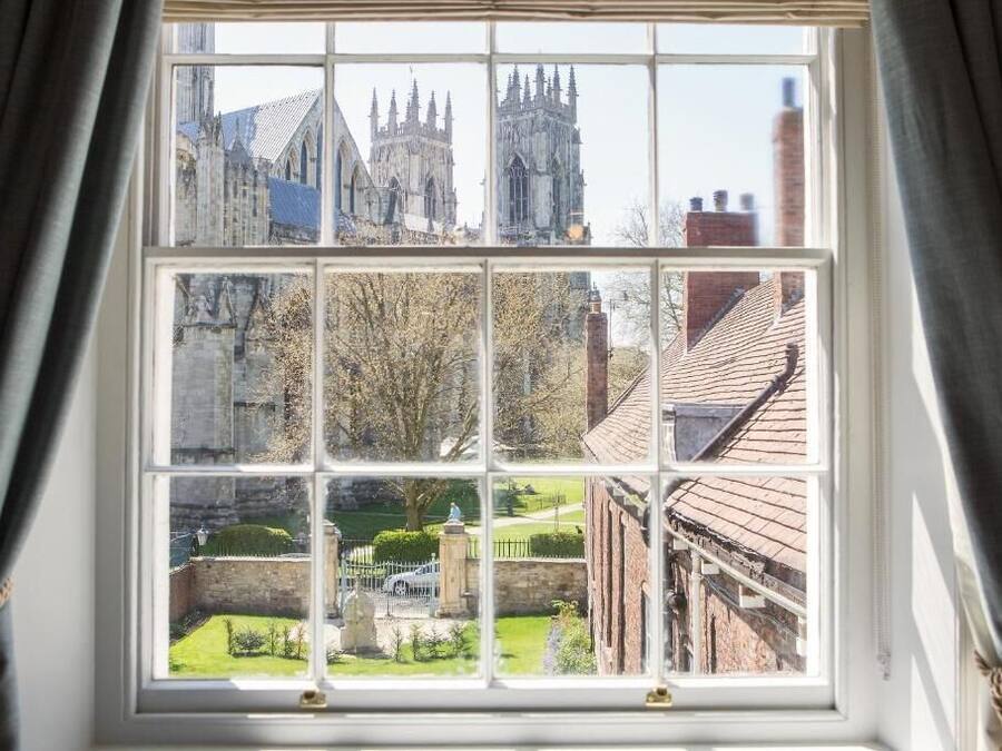 A window with a view of a historic building and a well-maintained garden.
