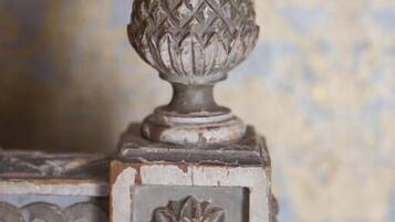A decorative metal piece with a spherical top and a floral design on a wall.
