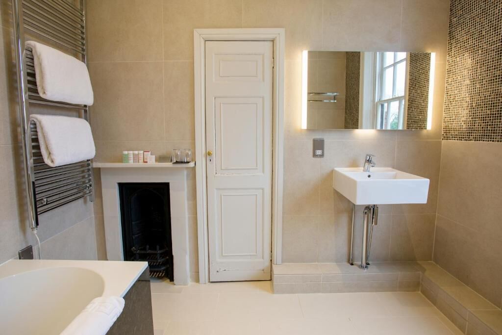 A bathroom with a bathtub, a white sink, a mirror, and a door.
