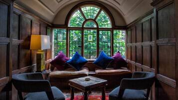 A cozy room with a wooden bench, two armchairs, a small table, and a colorful rug.