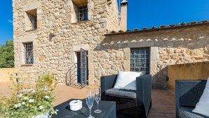 Ein Steinhaus mit Terrasse, Sitzgelegenheiten im Freien und einem Tisch mit Gläsern.