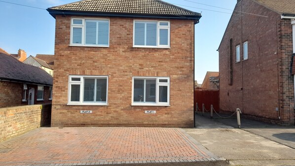 A two-story brick house with three windows, each with white shutters. - Captivating 2-bed Apartment in Bridlington (Bridlington)