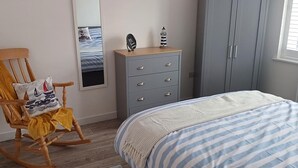 Makuuhuone, jossa on sänky, lipasto, keinutuoli ja vaatekaappi.