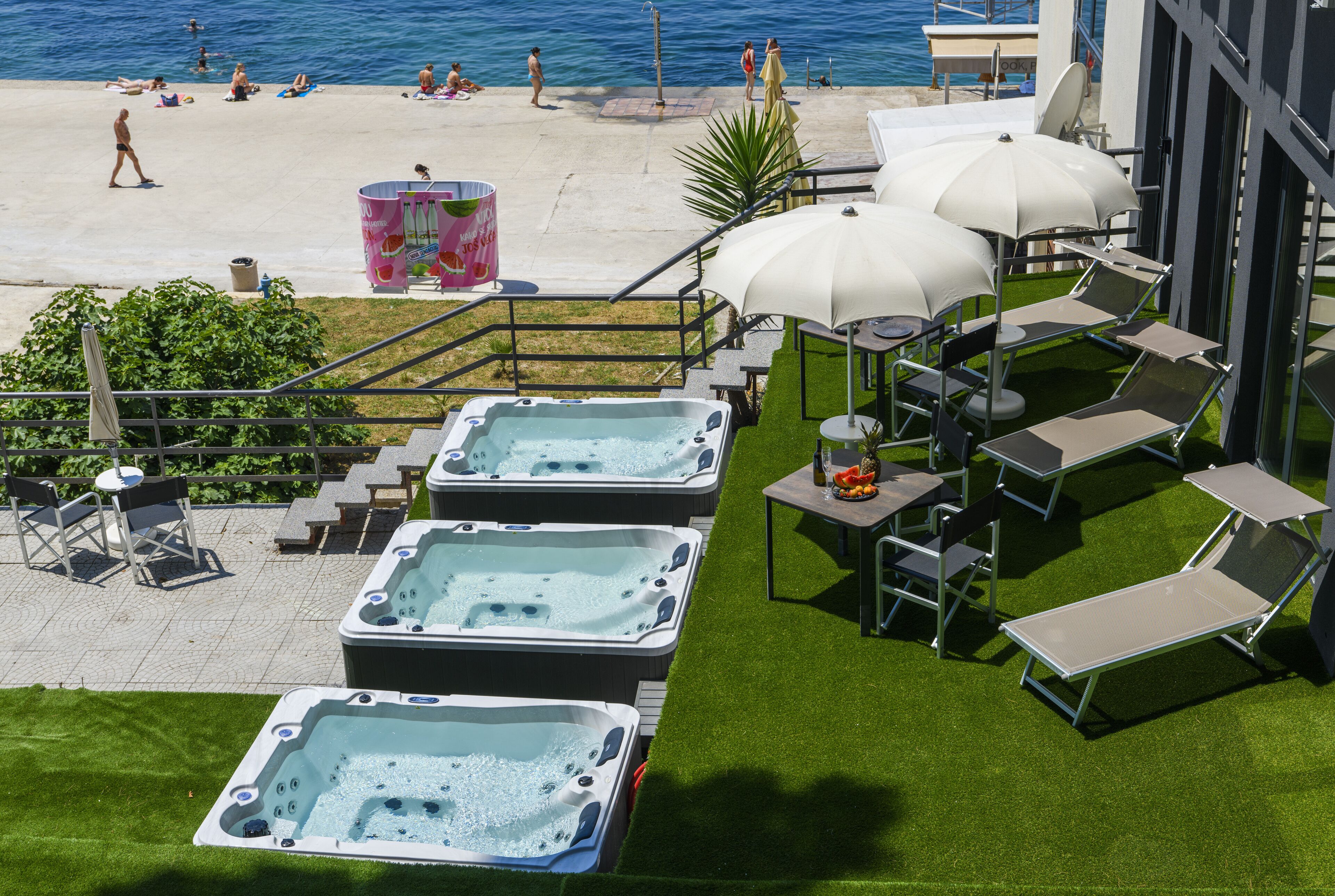 Une terrasse sur le toit dotée de jacuzzis, de chaises longues et de parasols, offrant une vue sur la plage.
