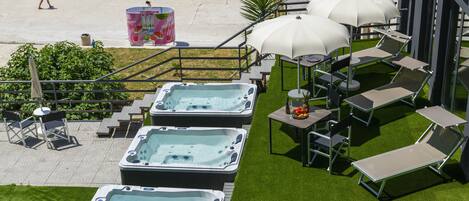 Une terrasse sur le toit dotée de jacuzzis, de chaises longues et de parasols, offrant une vue sur la plage.