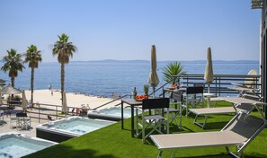 Un espace piscine aménagé sur le toit, avec des chaises longues, un jacuzzi et une vue sur la plage et la mer.