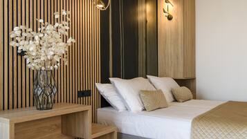 A modern bedroom with a wooden slat wall, a bed with white bedding, and a bedside table with a vase of flowers.