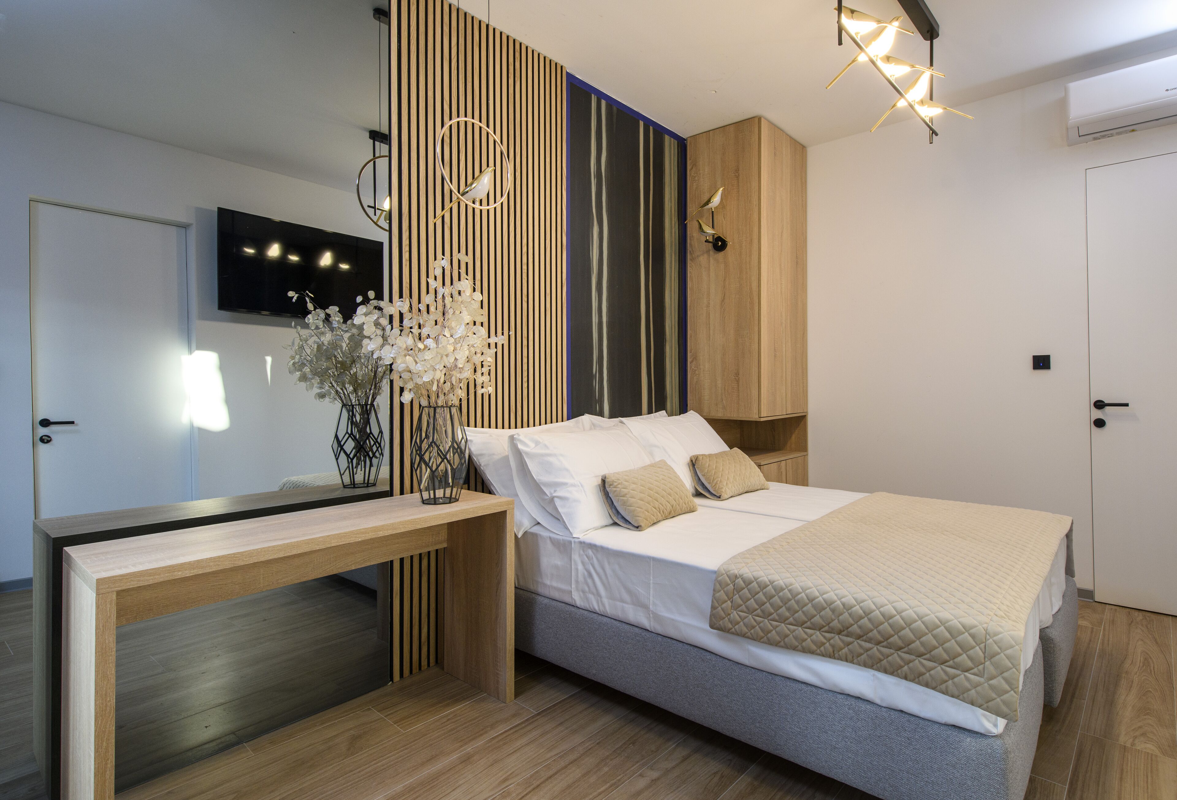 A modern bedroom with a bed, bedside table, and a wall-mounted TV.