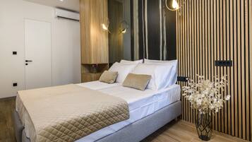 Une chambre à coucher moderne avec un lit, des tables de chevet, un vase de fleurs et un mur d’accent en bois.