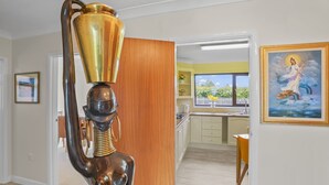 A modern kitchen with wooden cabinets, a dining area with a table and chairs, and a view of a garden through a window. - House - Sleeps 6 & Free Parking, Pets (Great Yarmouth)