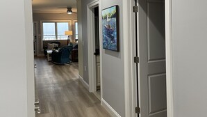 A hallway with wooden flooring, a ceiling fan, and a painting on the wall. - The Surf - steps to the beach (Hampton)
