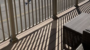 A beach view from a balcony with a railing, a bench, and a wicker table. - The Surf - steps to the beach (Hampton)