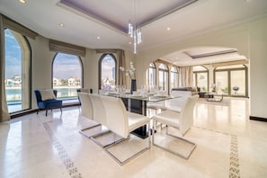 A spacious dining area with a high ceiling, large windows, and a view of the city.