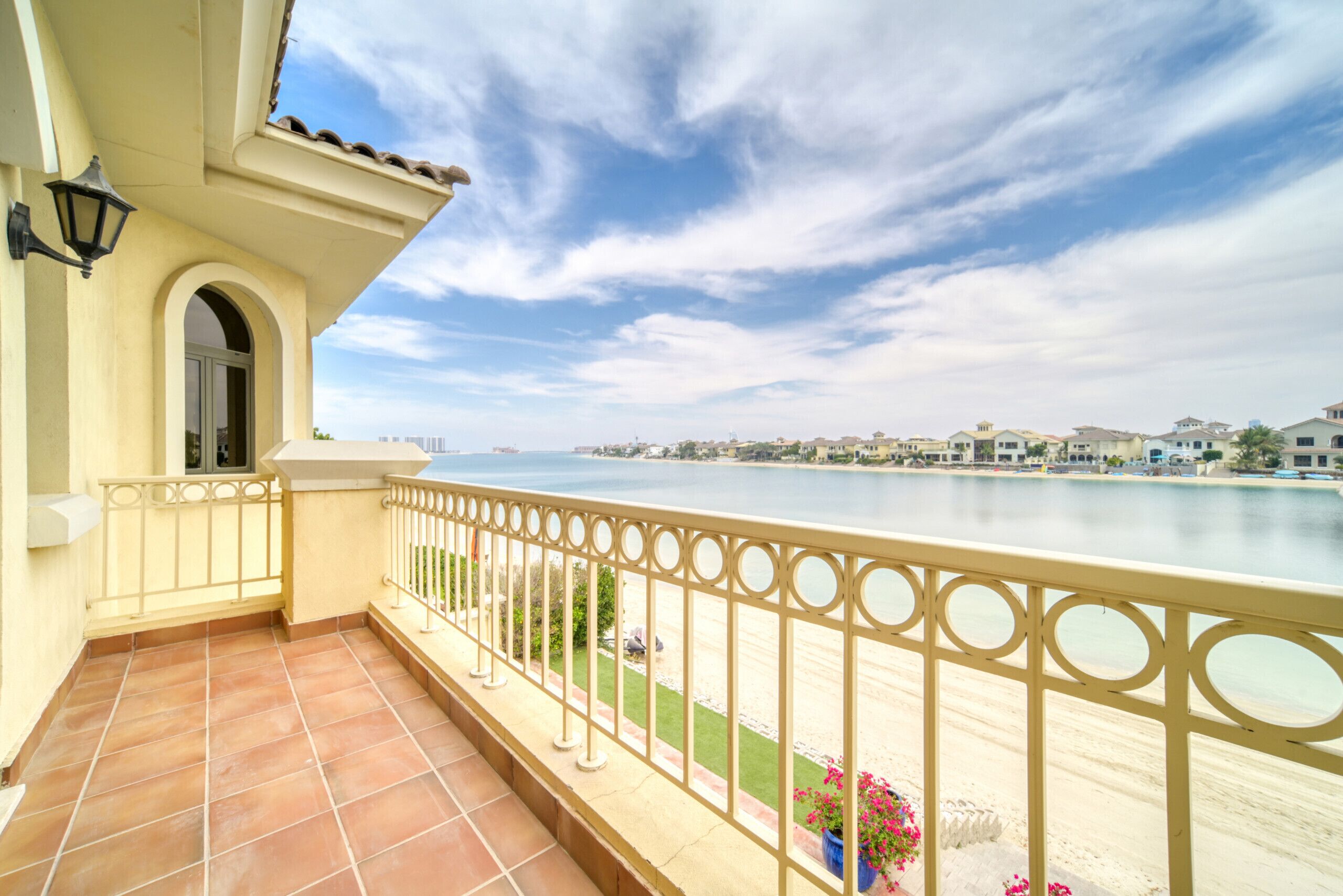 Un balcón con vista al mar, piso de baldosas y barandilla.