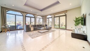 A spacious living room with a large sofa, coffee table, and a flat-screen TV.