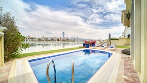 A swimming pool with a view of a city skyline and a body of water in the background.