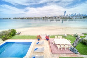 Ein Poolbereich mit Blick auf Strand und Stadtpanorama.