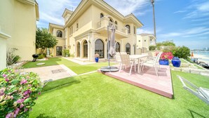 A large, two-story house with a patio, outdoor furniture, and a view of the ocean.