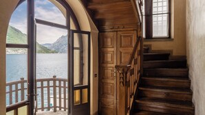 Eine Holztreppe führt zu einem Balkon mit Blick auf einen See und Berge.