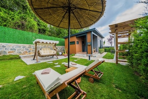 A backyard with a wooden swing set, a covered seating area, and a small building with a stone wall. - ON7 Sapanca Private  (Sapanca)
