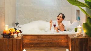 Un cuarto de spa con una bañera de madera, velas y un frutero.