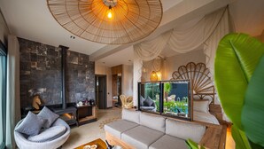 Una sala de estar moderna con chimenea de piedra, un sofá, una mesa de centro con aperitivos y un espejo grande que refleja la habitación.