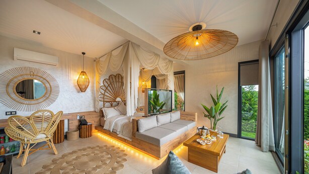 Un dormitorio moderno con cama, sofá, mesita de centro y un amplio ventanal.