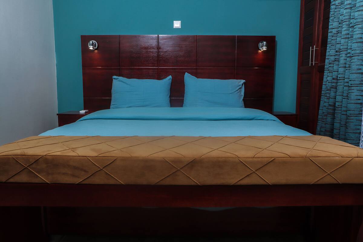 Una cama con cabecera de madera, dos almohadas y una colcha marrón.