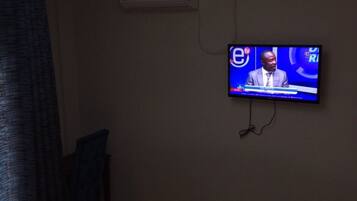 A room with a television mounted on the wall displaying a news program.