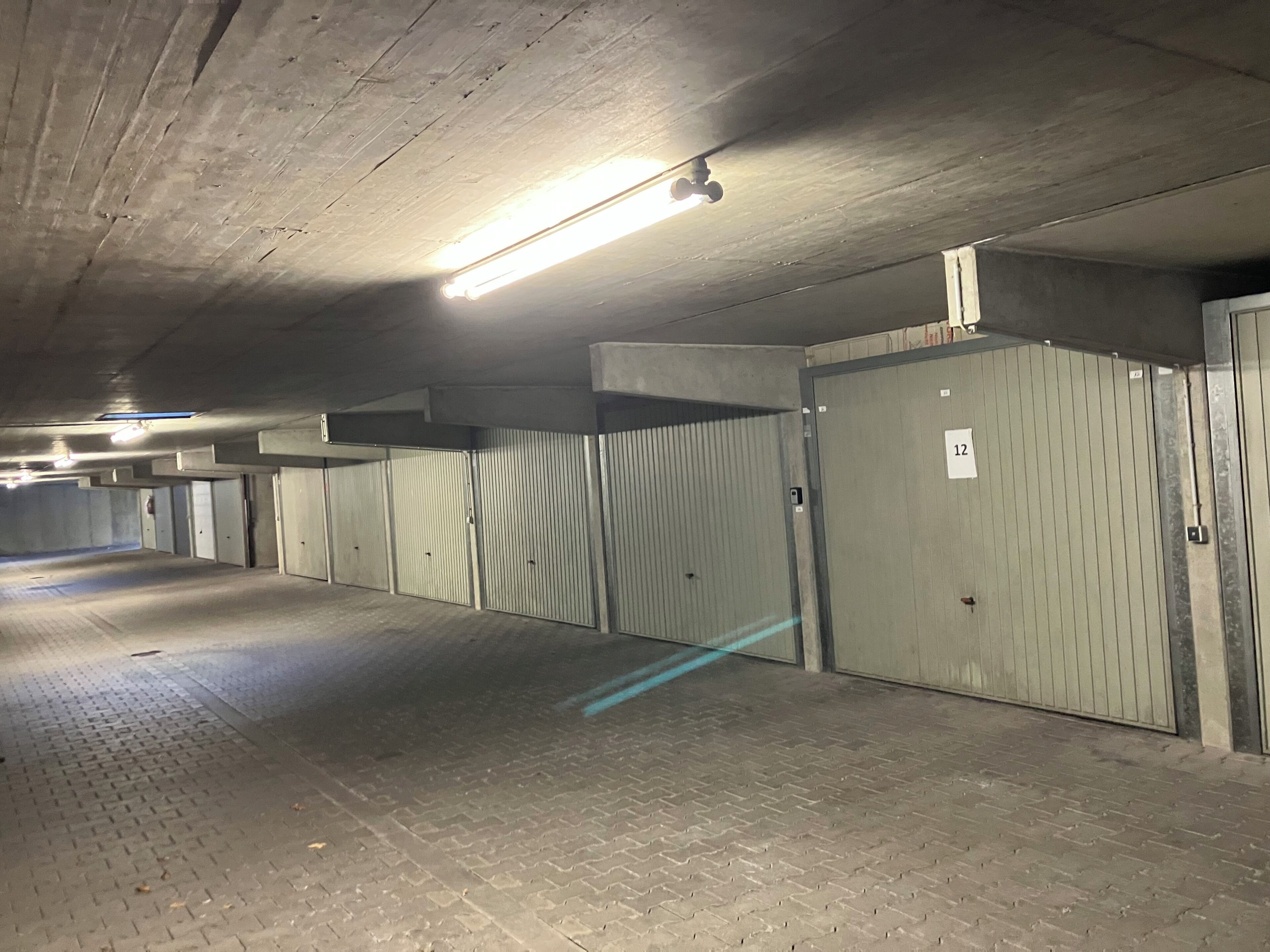 Un parking avec des planchers en béton, des portes métalliques et un éclairage fluorescent.
