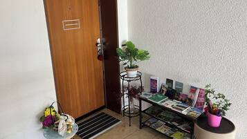 A room with a wooden door, a small table with a plant, a magazine rack, and a decorative item on the floor.