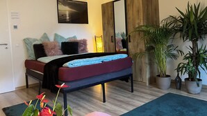 Een slaapkamer met een bed, een houten garderobe, een spiegel en potplanten.