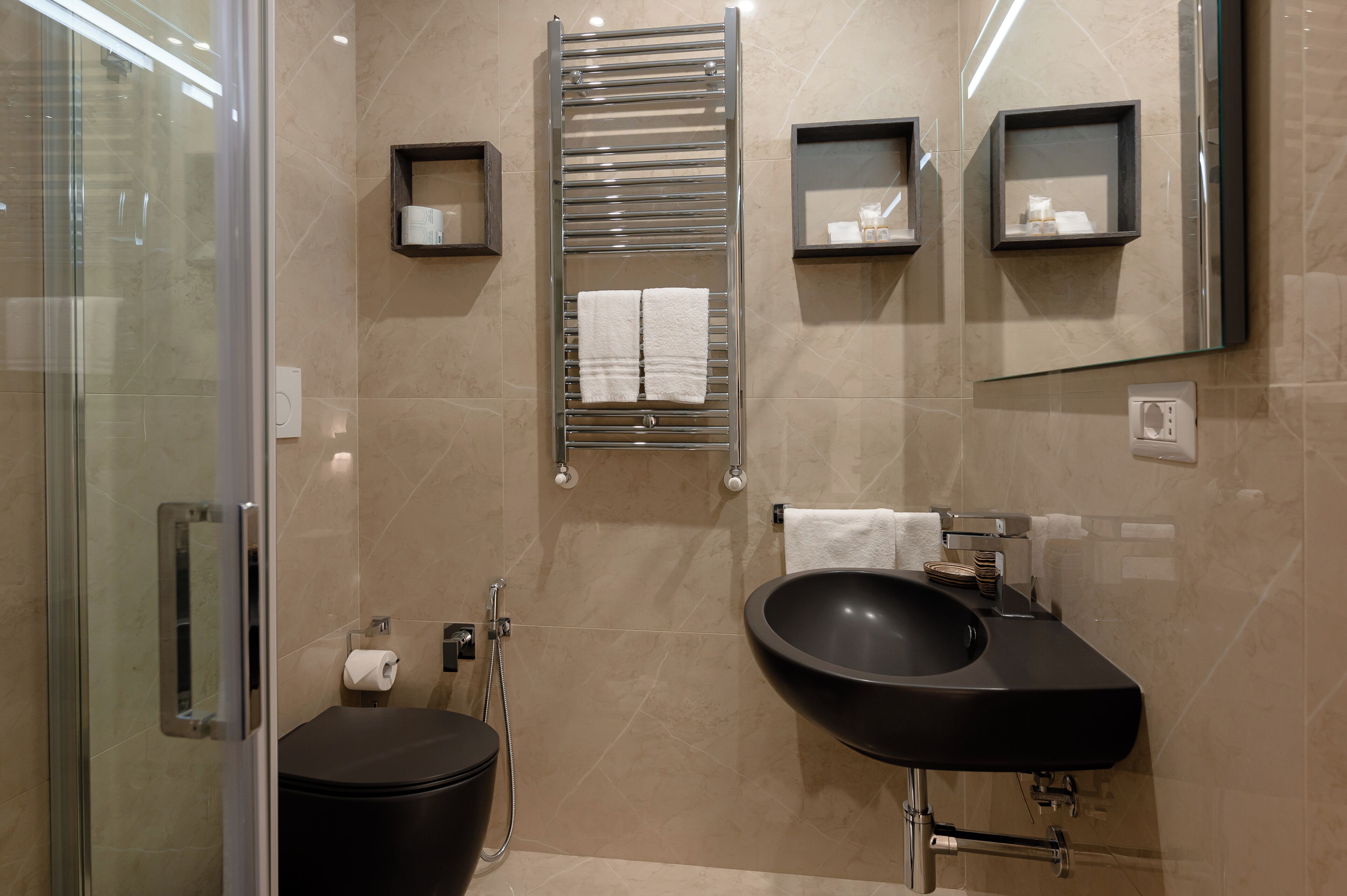 Une salle de bain moderne avec une douche à parois de verre, un lavabo noir et un porte-serviettes.