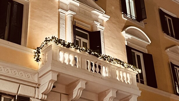 En byggnad med flera våningar som har klassiska arkitektoniska detaljer, inklusive utsmyckade balkonger och dekorativa lister.