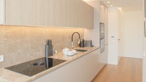 A modern kitchen with a built-in stove, a sink, and a countertop. - Liiiving - Crystal Palace Apartment (Porto)