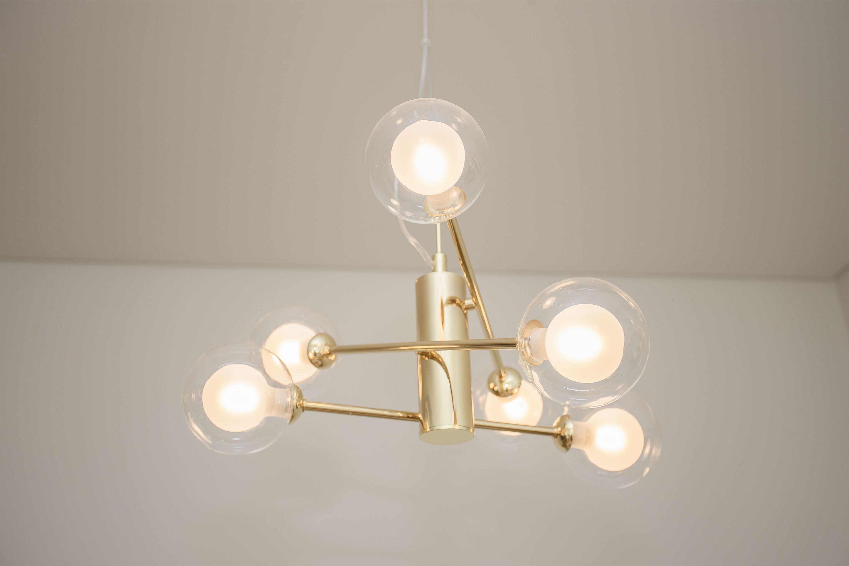 Un lampadario con diverse lampade sferiche in vetro e struttura in metallo dorato.