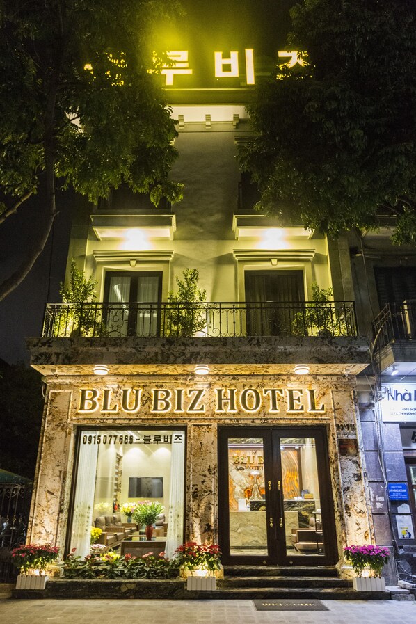 Het uiterlijk van Hotel Blu Biz, met een opvallende ingang, een balkon en een goed verlichte gevel.