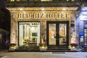 Het uiterlijk van Hotel BluBiz, met een marmeren gevel, grote glasramen en plantenpotten bij de ingang.