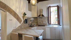 A kitchen with a marble countertop, white chairs, a built-in stove, and a window with curtains. - Trastevere Center, just a short walk from Piazza Trilussa (Roma)